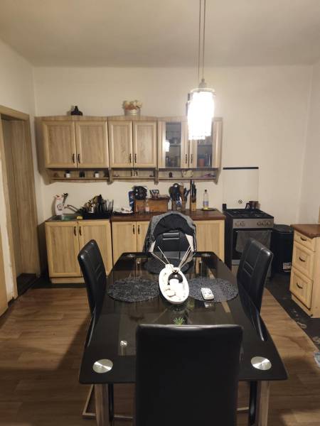 Na predaj 3-izb. rodinný dom, Gabčíkovo – Polná ulica - Jedáleň v rodinnom dome s jedálenským stolom a presklenými skriňami, podlaha s dreveným dekorom.