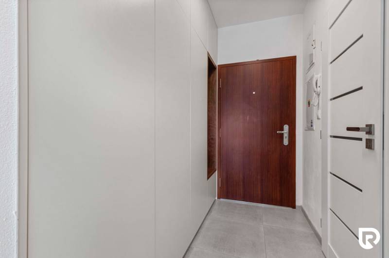 | Krásny a moderný 2-izbový byt | 51,50m² | - Vstupná chodba v 2-izbovom byte s bielymi stenami a tmavými dverami.