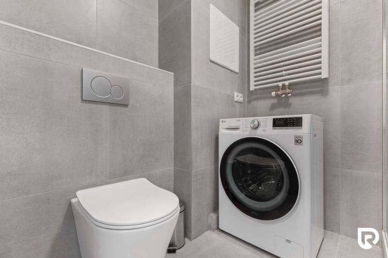 | Krásny a moderný 2-izbový byt | 51,50m² | - Kúpeľňa v 2-izbovom byte so sivými obkladačkami, toaletou a práčkou.