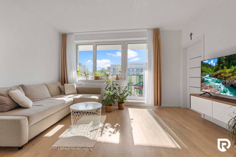 | Krásny a moderný 2-izbový byt | 51,50m² | - Obývacia izba v 2-izbovom byte s pohovkou a balkónovými dverami. Podlaha s dreveným dekorom.