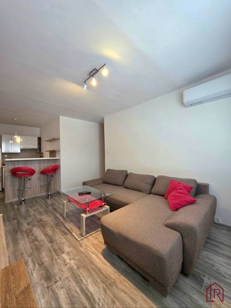 Prenájom, 1,5i Terasa, Kežmarská, zariadený - Obývacia izba 2-izbového bytu s tmavým nábytkom a podlahou s dreveným dekorom.