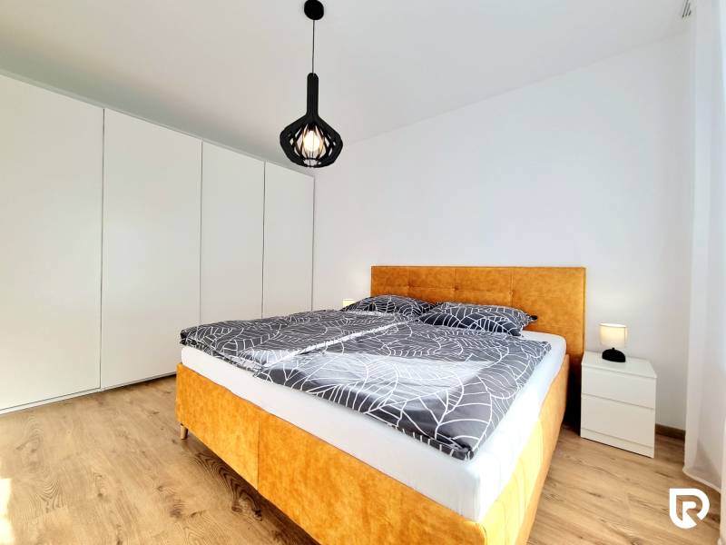 Posledný investičný krásny 2-izbový byt | 62 m² | RÍNOK RAČA - Spálňa v 2-izbovom byte s posteľou, bielymi stenami a podlahou s dreveným dekorom.