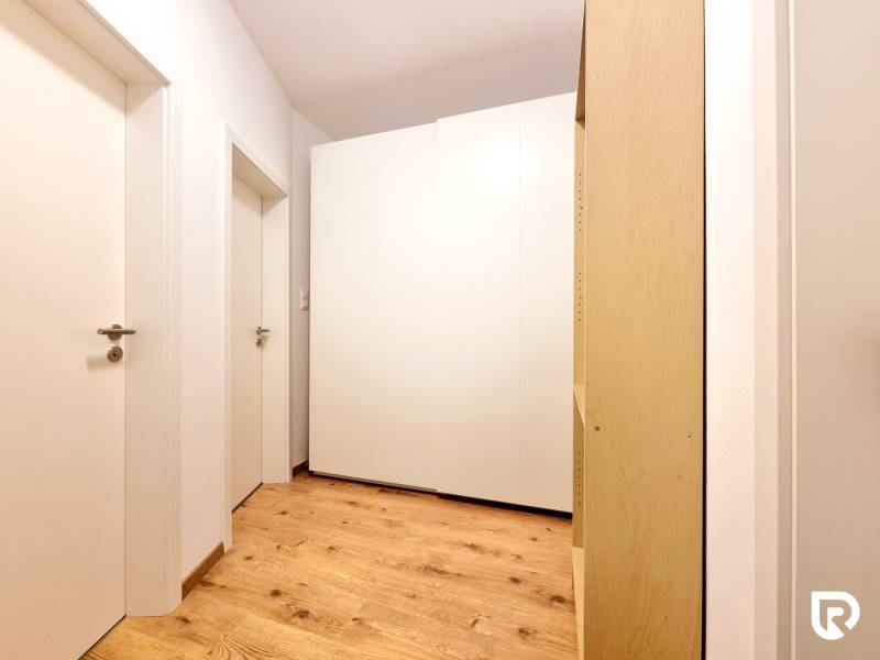 Posledný investičný krásny 2-izbový byt | 55 m² | RÍNOK RAČA - Biela skriňa a drevená podlaha na chodbe v 2-izbovom byte.