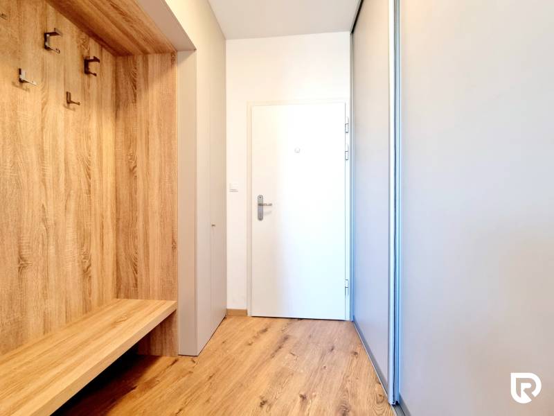Posledný investičný krásny 2-izbový byt | 55 m² | RÍNOK RAČA - Chodba 2-izbového bytu s podlahou s dreveným dekorom a bielymi stenami.