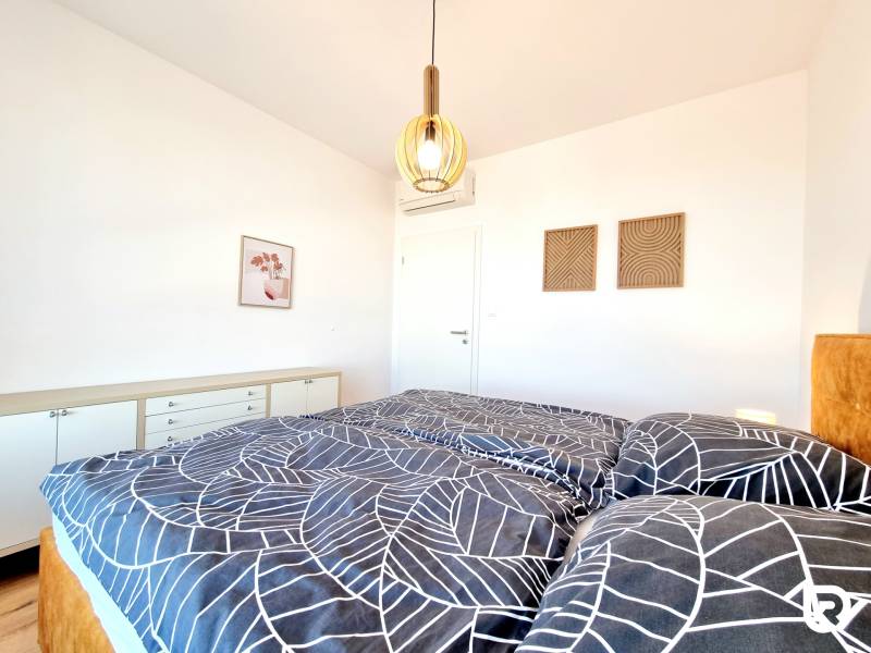 Posledný investičný krásny 2-izbový byt | 55 m² | RÍNOK RAČA - Svetlá spálňa v 2-izbovom byte s dekorom, posteľou a bielym nábytkom.