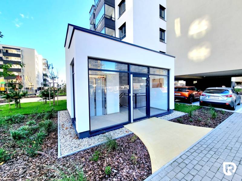 Posledný investičný krásny 2-izbový byt | 55 m² | RÍNOK RAČA - Chodník vedúci k presklenej budove, okolo sú upravené záhrady a parkovisko.