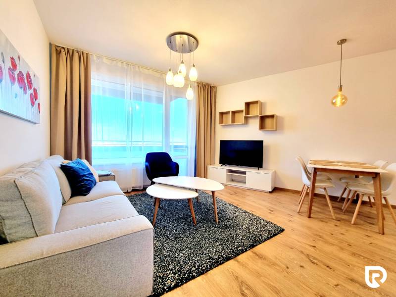 Posledný investičný krásny 2-izbový byt | 55 m² | RÍNOK RAČA - Obývačka v 2-izbovom byte s podlahou s dreveným dekorom, sedačkou a jedálenským stolom.