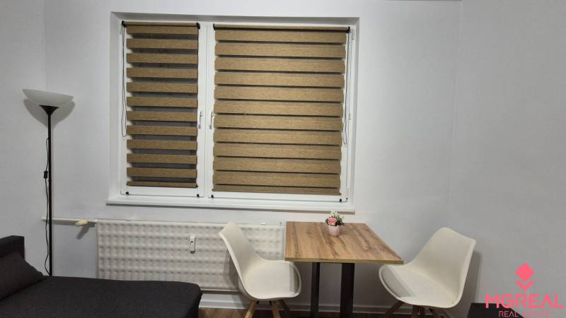 Prenájom 1- izbový byt  - Jedálenský kút s dreveným stolíkom a dvoma bielymi stoličkami v 1-izbovom byte.