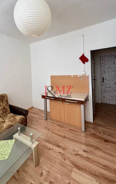 Predaj garsónky – Tlmače, Lipník- ihneď voľná (MK-3) - Garsónka s pohovkou, skleneným stolíkom a podlahou s dreveným dekorom.