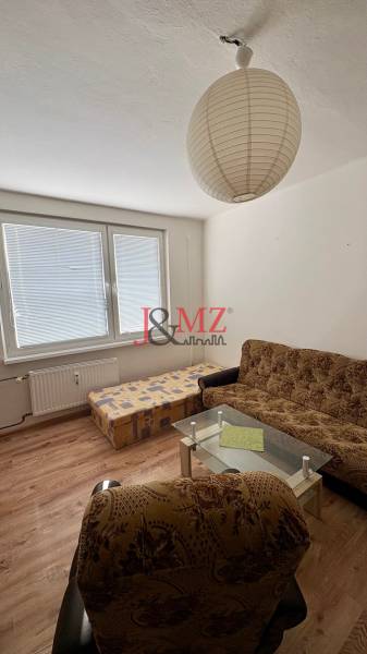 Predaj garsónky – Tlmače, Lipník- ihneď voľná (MK-3) - Garsónka obsahuje sedačku, kreslo, konferenčný stolík, podlahu s dreveným dekorom a veľké okno.