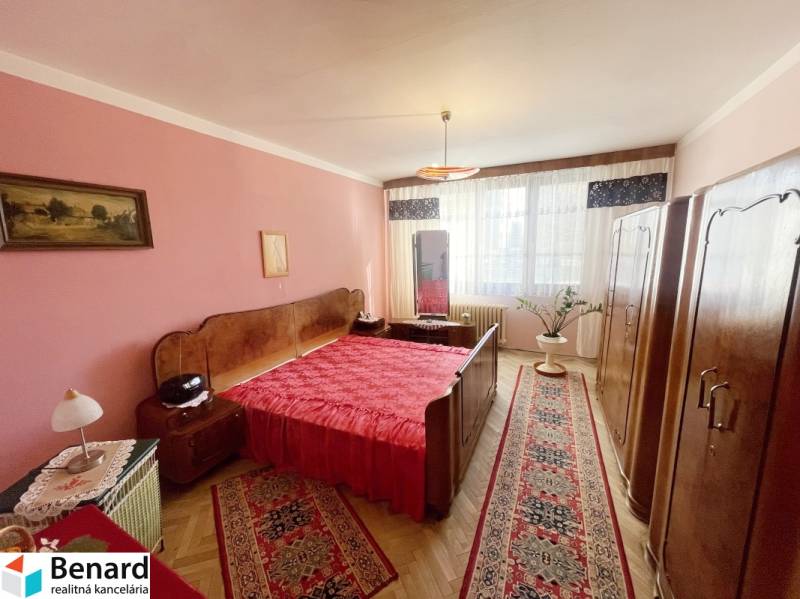 PREŠOV-3 IZBOVÝ BYT,LODŽIA,67m2,SÍDLISKO III.,MATICE SLOVENSKEJ - Spálňa v 3-izbovom byte s červenými doplnkami a podlahou s dreveným dekorom.