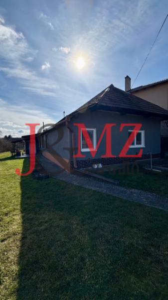 Útulný rodinný dom v tichej lokalite Mýtnych Ludán (MK-4) - Rodinný dom v Mýtnych Ludanoch, obklopený záhradou, s modrou oblohou a slnkom.