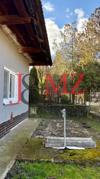 Útulný rodinný dom v tichej lokalite Mýtnych Ludán (MK-4) - Rodinný dom v Mýtnych Ludanoch s bočnou záhradkou a trávnikom, obklopený plotom.