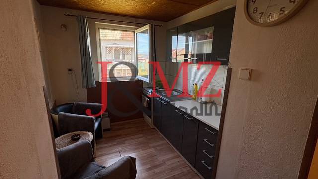 Útulný rodinný dom v tichej lokalite Mýtnych Ludán (MK-4) - Kuchyňa s podlahou s dreveným dekorom a tmavými skriňami v rodinnom dome.