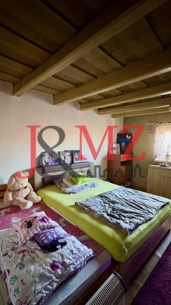 Útulný rodinný dom v tichej lokalite Mýtnych Ludán (MK-4) - Spálňa v rodinnom dome s dreveným stropom, posteľou a plyšovým medveďom.