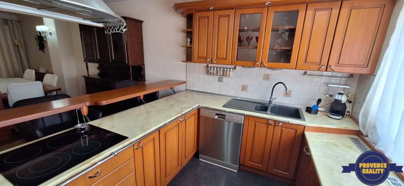 Luxusný rodinný dom s bazénom a dvojgarážou v Komárne - Kuchyňa v Rodinnom dome s drevenými skrinkami a nerezovou umývačkou riadu.