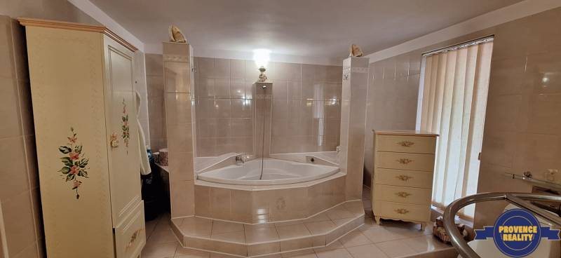 Luxusný rodinný dom s bazénom a dvojgarážou v Komárne - Kúpeľňa v rodinnom dome s rohovou vaňou a dekorovaným nábytkom.