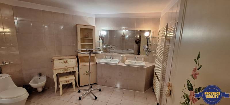 Luxusný rodinný dom s bazénom a dvojgarážou v Komárne - Kúpeľňa v rodinnom dome s dvomi umývadlami, zrkadlom a zdobeným nábytkom.