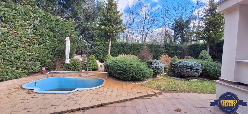 Luxusný rodinný dom s bazénom a dvojgarážou v Komárne - Rodinný dom v Komárne s malým bazénom a udržiavanou záhradou obklopenou stromami.