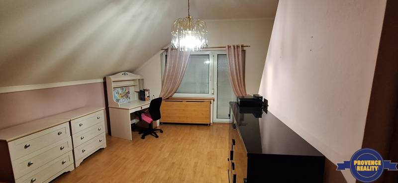 Luxusný rodinný dom s bazénom a dvojgarážou v Komárne - Izba s podlahou s dreveným dekorom, nábytkom a lustrom v rodinnom dome.