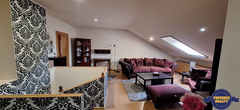 Luxusný rodinný dom s bazénom a dvojgarážou v Komárne - Obývacia izba s pohovkami a vzorovanými stenami, podlaha s dreveným dekorom.