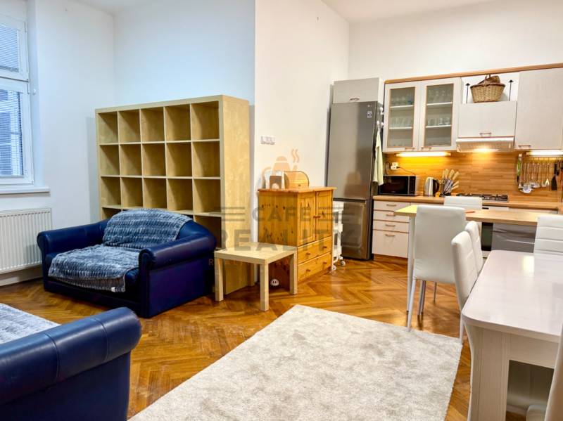 REZERVOVANÉ Na prenájom 3 izbový byt, 73 m2, Bratislava, Zochova - Obývacia izba 3-izbového bytu s kuchynským kútom, podlahou s dreveným dekorom a sedačkou.