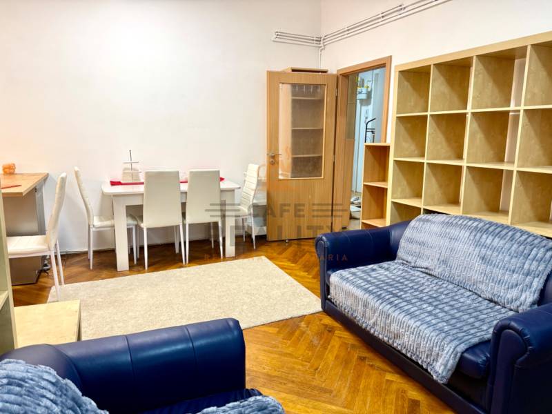 REZERVOVANÉ Na prenájom 3 izbový byt, 73 m2, Bratislava, Zochova - Obývačka v 3-izbovom byte s lavicou, jedálenským stolom a regálom, podlaha s dreveným dekorom.