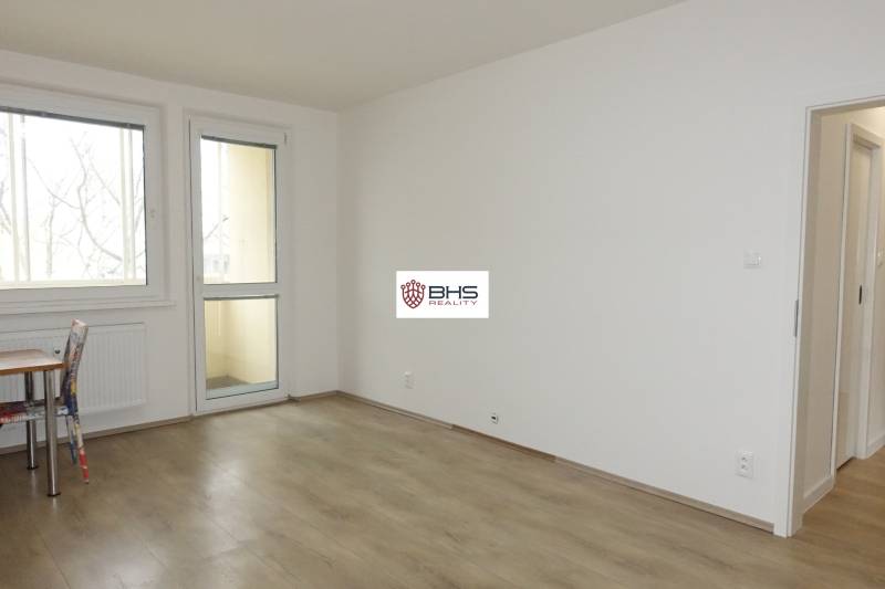 PRENÁJOM –  1 izba (príp. 2 izby) v 3-izb. byte, Gwerkovej ul., BA V - Izba s podlahou s dreveným dekorom v 3-izbovom byte, stôl a stolička.