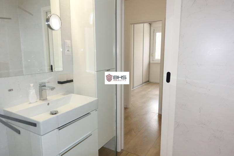 PRENÁJOM –  1 izba (príp. 2 izby) v 3-izb. byte, Gwerkovej ul., BA V - Kúpeľňa s umývadlom, bielou skrinkou a výhľadom do chodby v 3-izbovom byte.