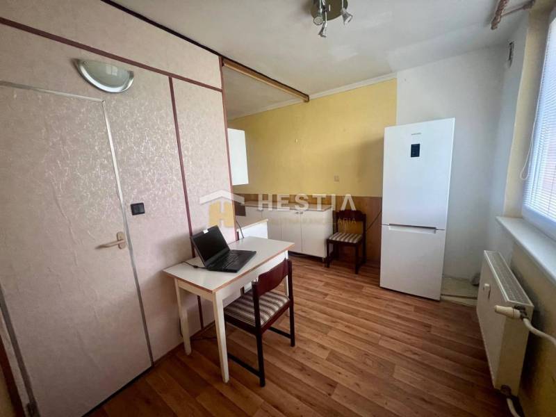 TOP 3 izbový byt v Moravskom Lieskovom s garážou a predzáhradkou - Kuchyňa v 3-izbovom byte s pracovným stolom, chladničkou a drevenou podlahou.