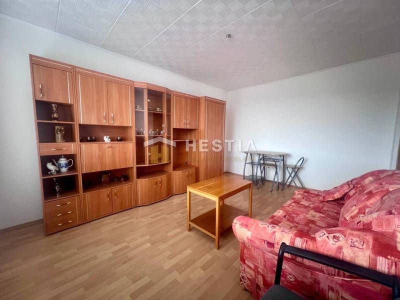 TOP 3 izbový byt v Moravskom Lieskovom s garážou a predzáhradkou - Obývacia izba v 3-izbovom byte s červenou sedačkou a drevenou obývacou stenou.