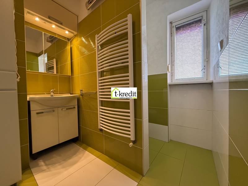 PREDAJ - 2i BYT - ZLATÉ MORAVCE - Kúpeľňa v 2-izbovom byte s umývadlom, zrkadlom a zeleno-bielymi obkladmi.