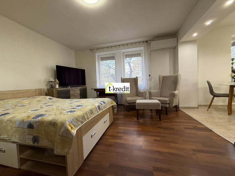 PREDAJ - 2i BYT - ZLATÉ MORAVCE - Spálňa v 2-izbovom byte s podlahou s dreveným dekorom a pohodlnými kreslami.