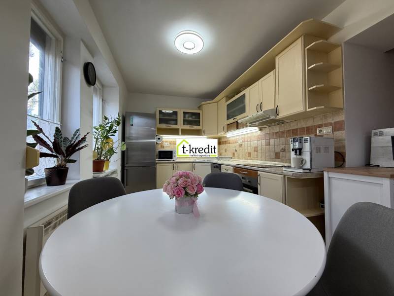 PREDAJ - 2i BYT - ZLATÉ MORAVCE - Kuchyňa v 2-izbovom byte s kuchynskou linkou, oknami a rastlinami.