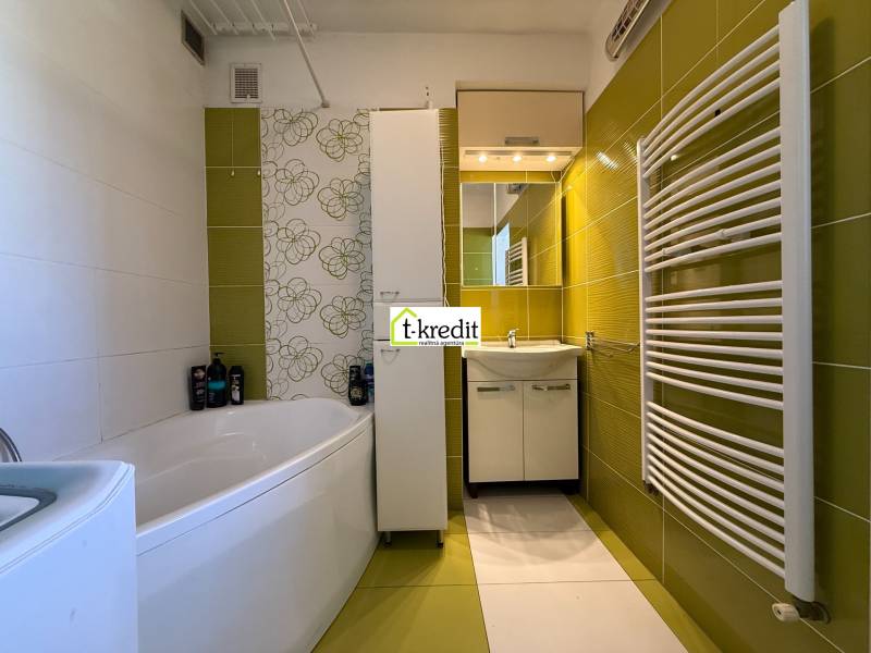 PREDAJ - 2i BYT - ZLATÉ MORAVCE - Kúpeľňa v 2-izbovom byte so zelenými obkladmi, vaňou a moderným vykurovacími telesom.