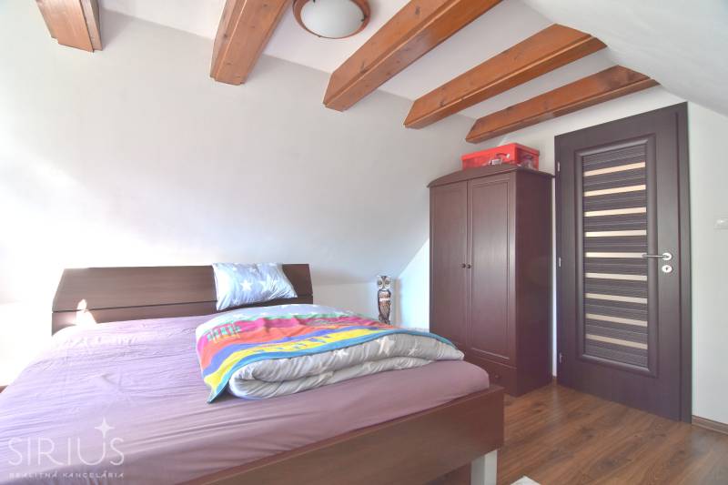 LIMBACH, 176 m2 –  kompletne zrekonštruovaný 5-i rodinný dom - Spálňa v podkroví s drevenými trámami, posteľou a skriňou, dom na ulici Limbach.