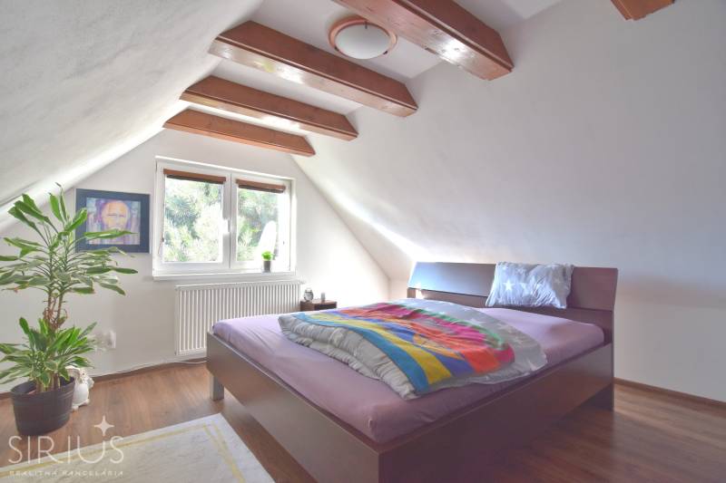 LIMBACH, 176 m2 –  kompletne zrekonštruovaný 5-i rodinný dom - Podkrovná spálňa s drevenými trámami, veľkým oknom a posteľou, priestor Limbach dom.