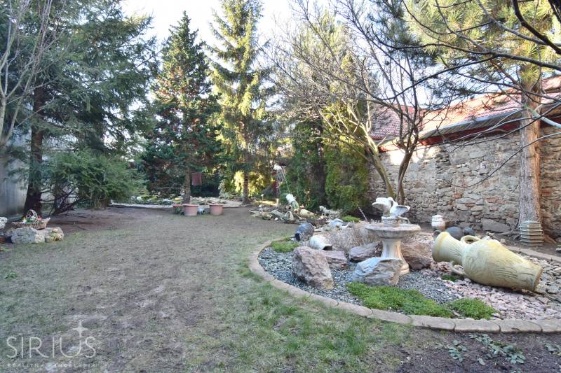 LIMBACH, 176 m2 –  kompletne zrekonštruovaný 5-i rodinný dom - Záhrada pri rodinnom dome, Limbach, so zeleňou, kamennými dekoráciami a starou kamennou stenou.