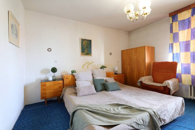 RD v jednej z najžiadanejších lokalít Michaloviec – pod Hrádkom - Spálňa s veľkou posteľou, drevenými skrinkami a kreslom v rodinnom dome.