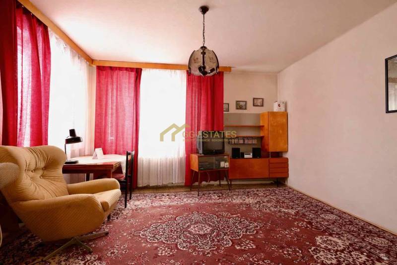 RD v jednej z najžiadanejších lokalít Michaloviec – pod Hrádkom - Obývačka v rodinnom dome s červeným kobercom, kreslom a závesmi na oknách.