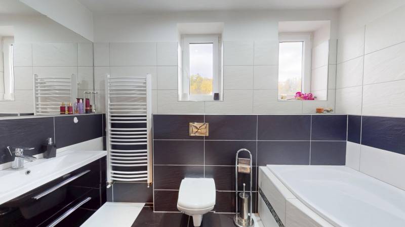 Prerobený rodinný dom na veľkom tichom pozemku v obci Pruské   - Kúpeľňa v rodinnom dome s vaňou, dlaždicami, umývadlom a oknami na stene.