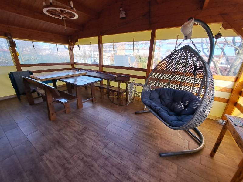 Predáme záhradu so zrubovou chatou, Nitra - Dolné Krškany - Oáza pokoja so závesným kreslom a dreveným nábytkom na podlahe s dreveným dekorom v Záhradách.