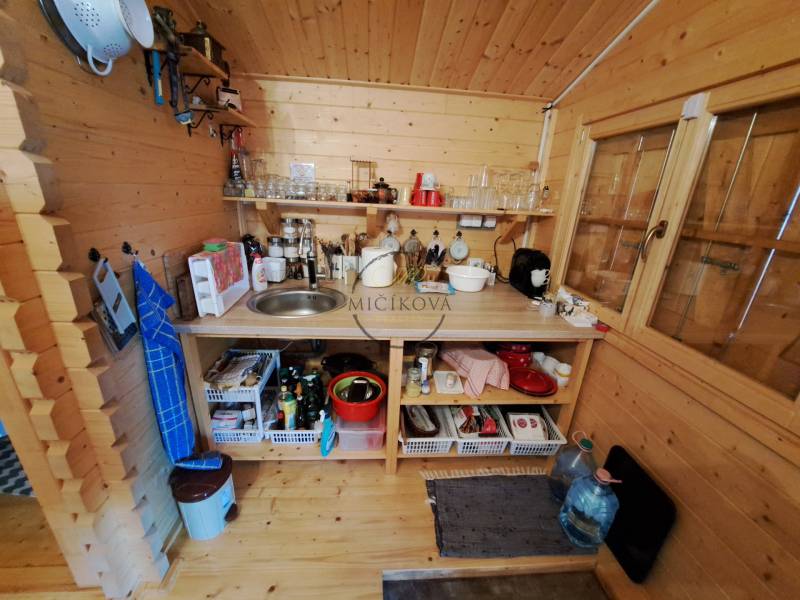 Predáme záhradu so zrubovou chatou, Nitra - Dolné Krškany - Drevená kuchynka so spotrebičmi, poličkami a drezom v interiéri Záhrad.