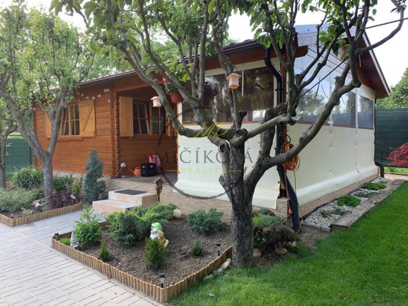 Predáme záhradu so zrubovou chatou, Nitra - Dolné Krškany - Drevený záhradný domček obklopený zeleňou v záhradách Dolných Krškanoch v Nitre.