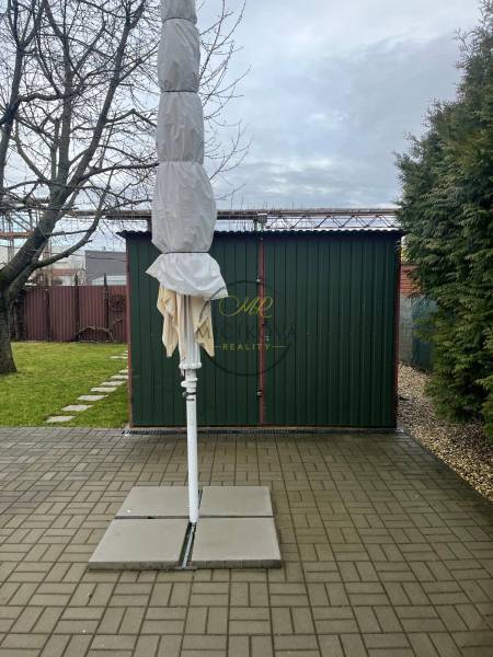 Predáme záhradu so zrubovou chatou, Nitra - Dolné Krškany - Záhrady v Dolných Krškanoch v Nitre s poskladaným slnečníkom, spevnenou plochou a trávnikom.