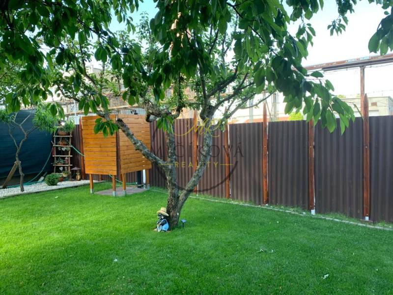 Predáme záhradu so zrubovou chatou, Nitra - Dolné Krškany - Záhrady v Dolných Krškanoch, Nitra, s trávnikom, stromom, malým dreveným domčekom a plotom.