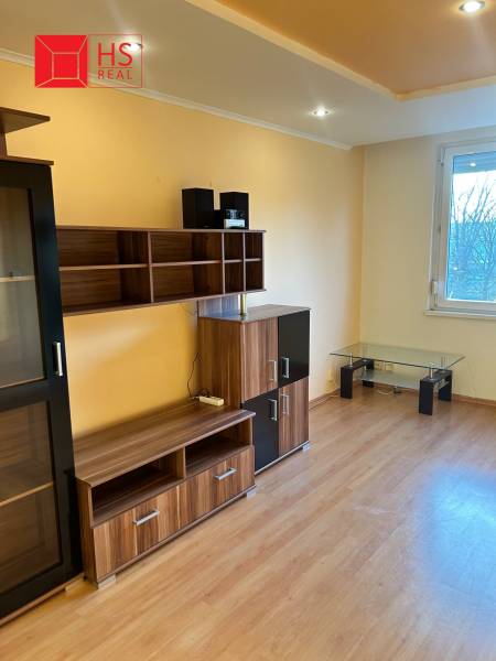 Predaj 3 izb. bytu s balkónom v NZ - Obývacia izba v 3-izbovom byte s nábytkom a podlahou s dreveným dekorom.