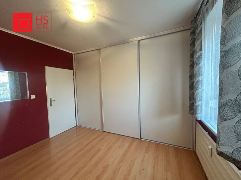 Predaj 3 izb. bytu s balkónom v NZ - Izba v 3-izbovom byte s podlahou v drevenom dekore a vstavanou skriňou.