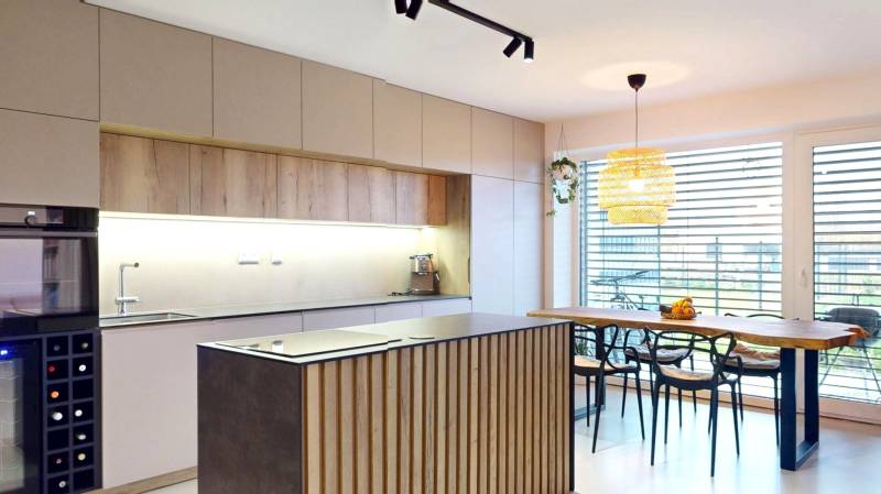 Novozariadený rodinný dom s veľkými spálňami i šatníkom pri Trenčíne   - Kuchyňa v rodinnom dome s dreveným dekorom nábytku a veľkými oknami.