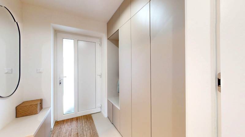 Novozariadený rodinný dom s veľkými spálňami i šatníkom pri Trenčíne   - Vstupná chodba rodinného domu s vešiakovou skriňou, zrkadlom a kobercom.